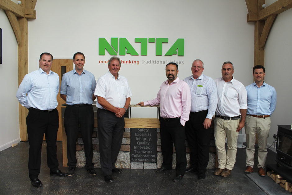 Natta’s Management Team standing beside our bespoke reception desk which incorporates a statement of our core values