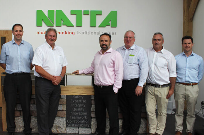 Natta’s Management Team standing beside our bespoke reception desk which incorporates a statement of our core values