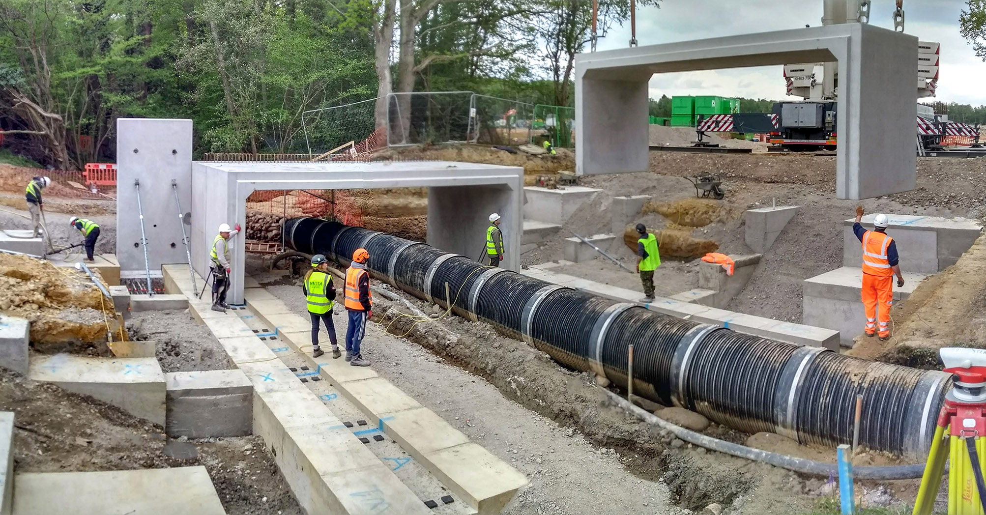 Construction workers installing large drainage culverts and concrete sections for a bridge at Copthorne.