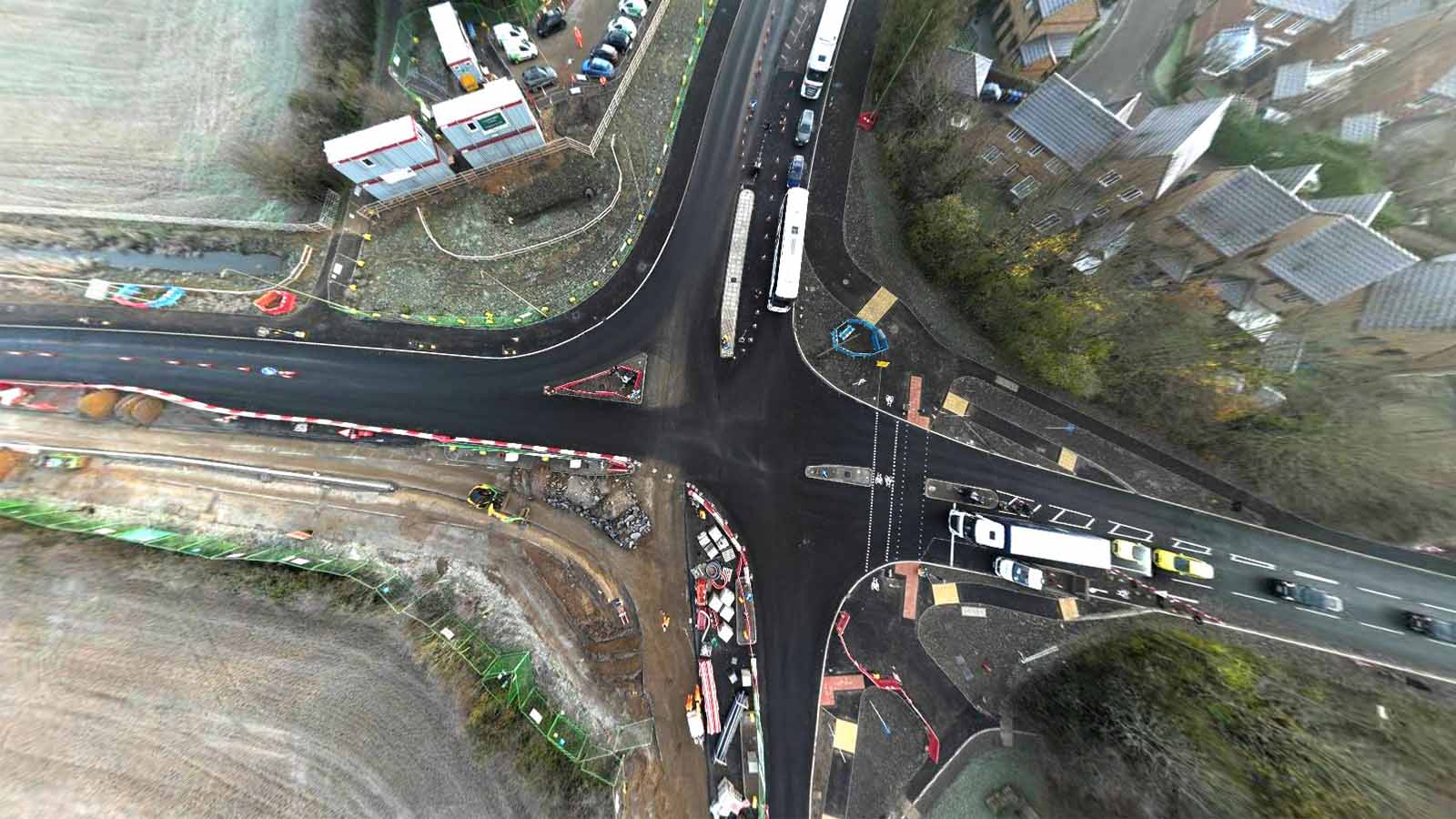 Aerial view of a newly constructed road junction with fresh asphalt, road markings, and active traffic with a four-way intersection with multiple lanes and pedestrian crossings - Banbury Road, Bicester - Section 278