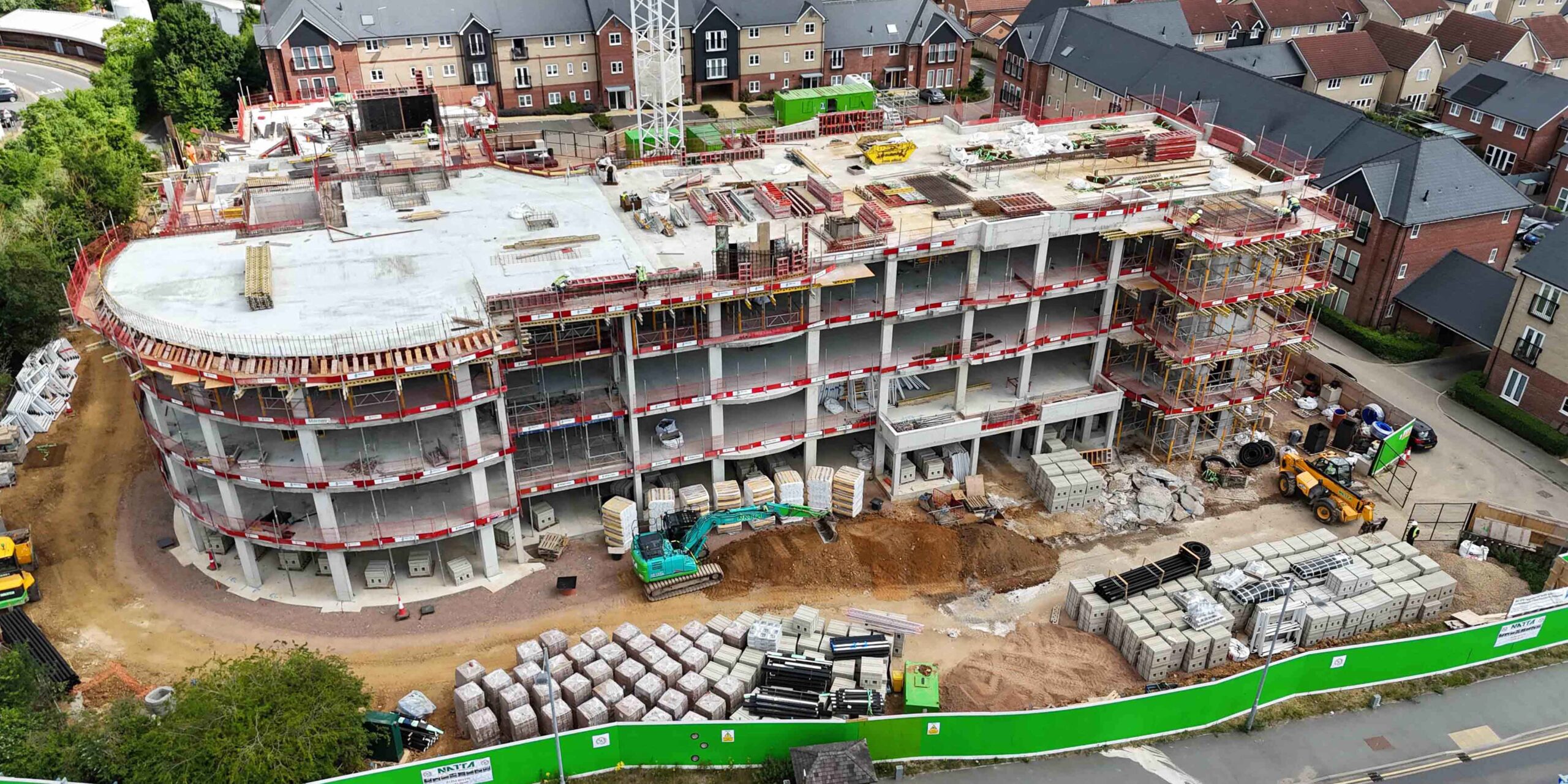 A low, front aerial view of a multi-storey care home under construction made from concrete.