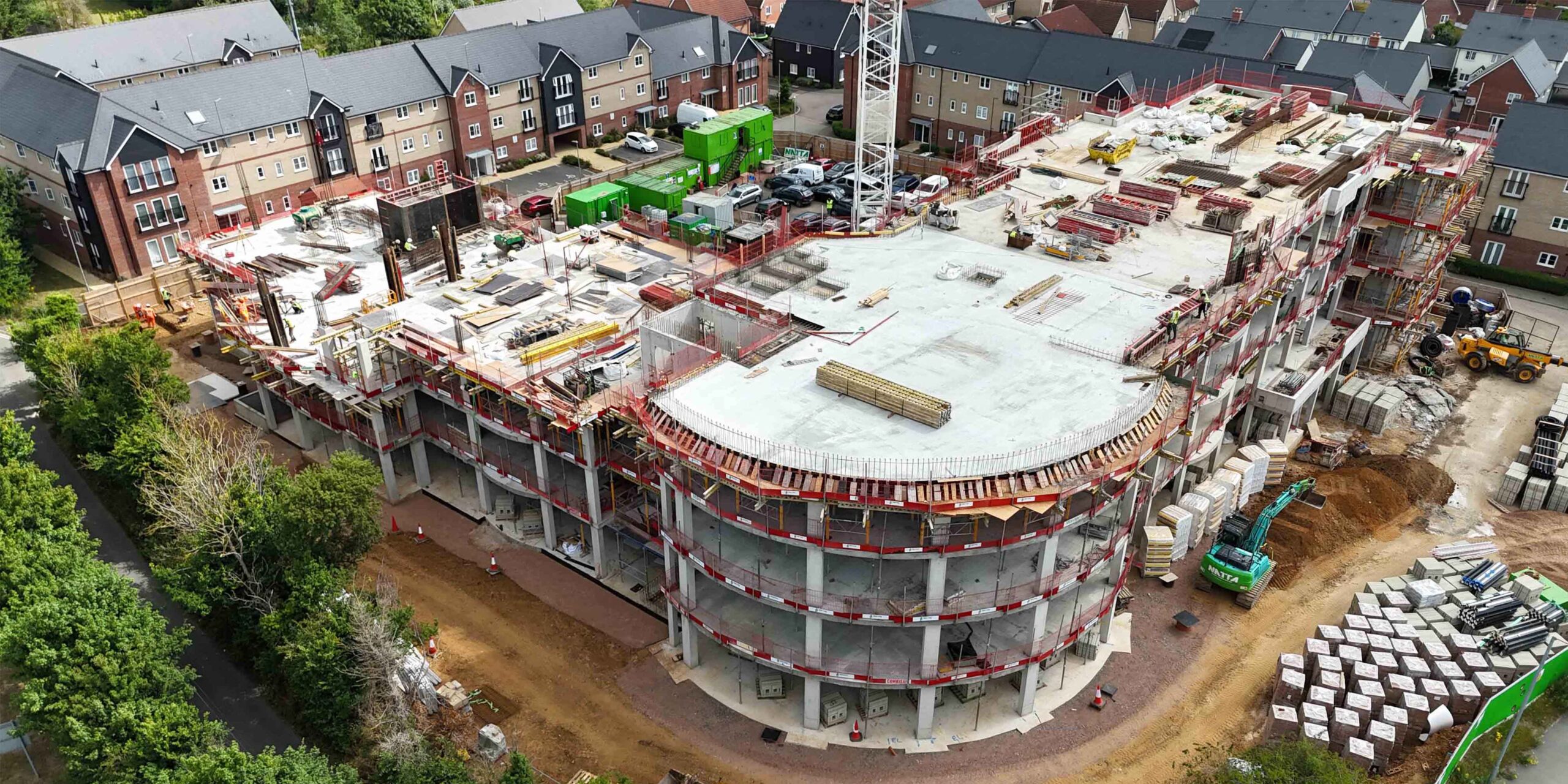 Side aerial view of a multi-storey concrete care home building under construction.